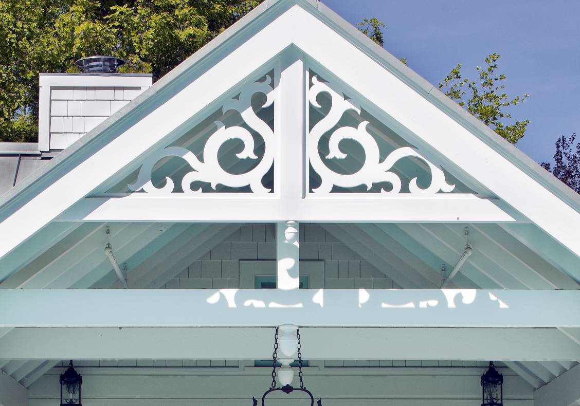 Water jet cut victorian scroll gable ornamentation gives a playful, cheerful frame to the covered dining porch overlooking the pool.