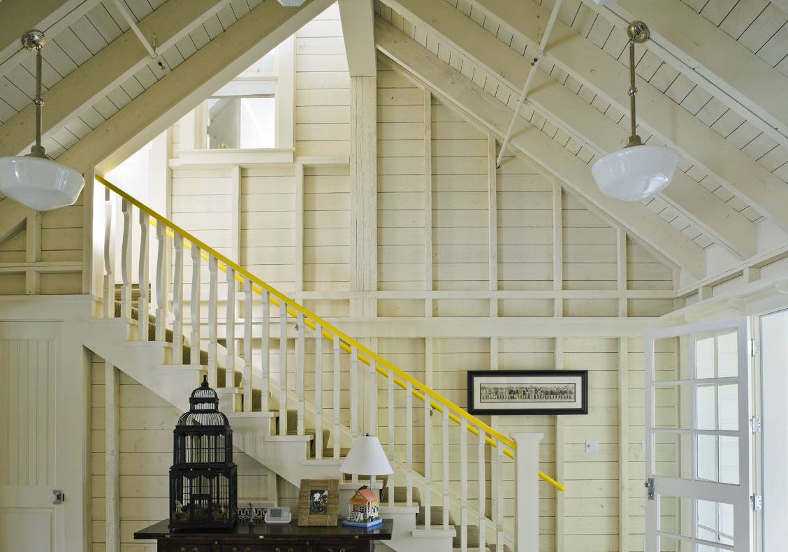 Open stud framing whitewashed with bright yellow railing and interior window to guest bedroom.