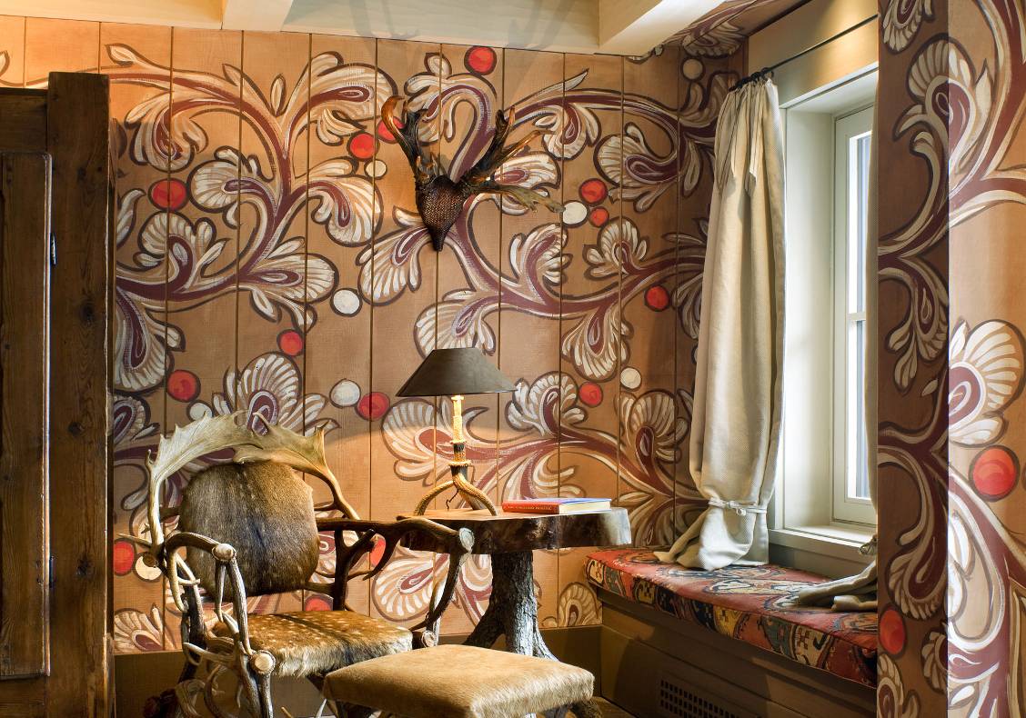 Master bedroom with window seat, paisley-painted walls, and antique antler furnishings.