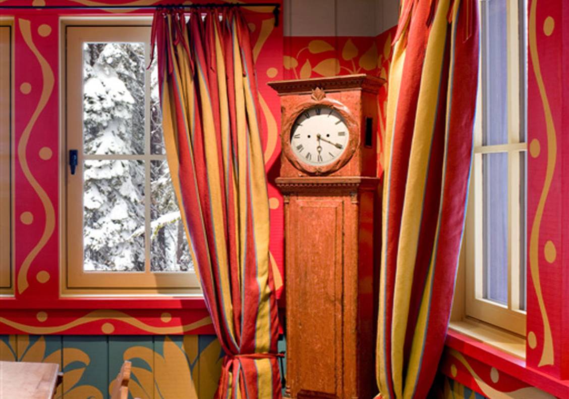 Dining room with whimsical walls, curtains, and grandfather clock.