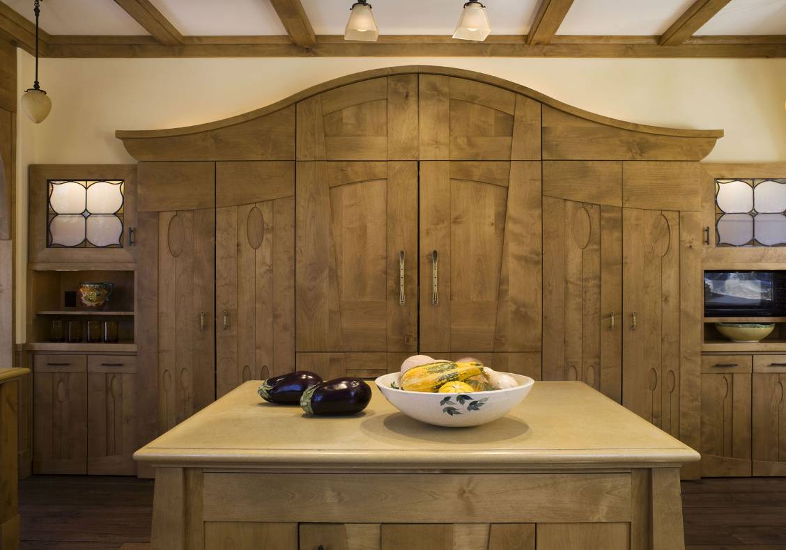 A stained island with carved cut outs and butcher block countertop offsets the richly painted kitchen cabinets.