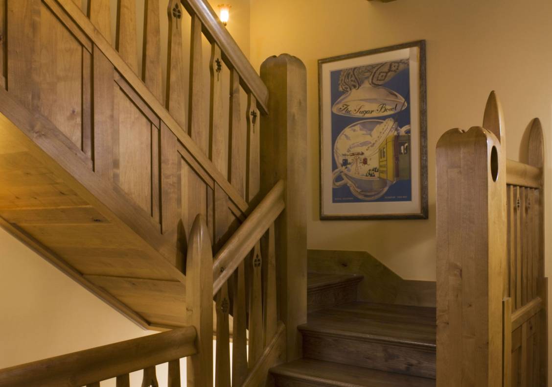 Carved newel posts and water jet cut balusters crafted from stained alder wood form the central skylit stairway of this home.