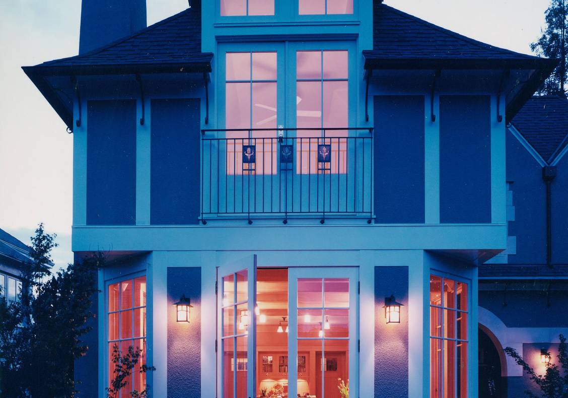 Evening view of the house with family room wing and master bedroom Juliet balcony above.