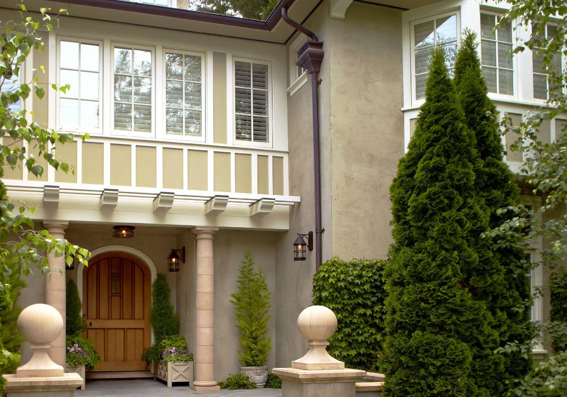 Cast stone bollards, bluestone porch steps, rendered gables, quartersawn oak door.