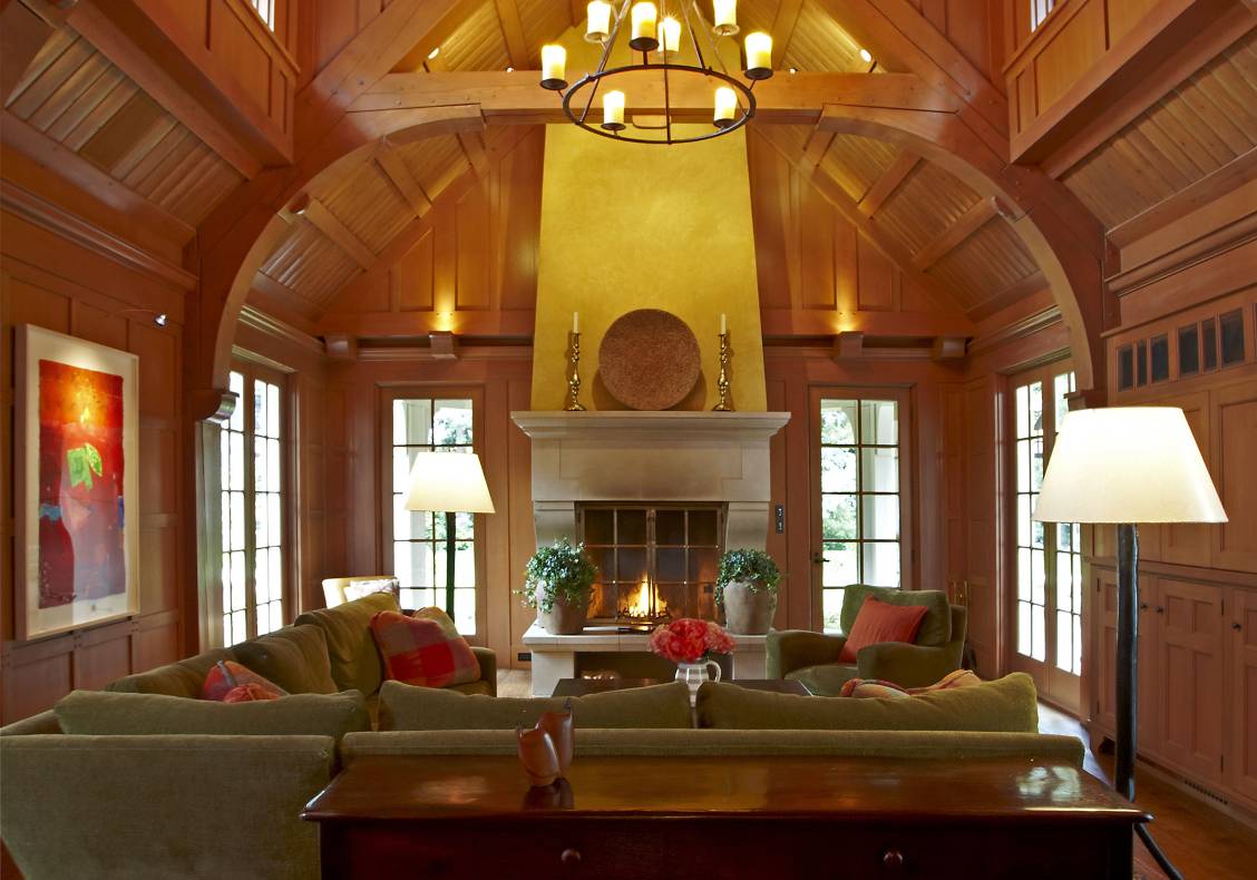 English country great room with heavy timber trusses, cast stone fireplace, bronze fireplace doors, stained douglas fir millwork, waxed plaster chimney, candle lantern.