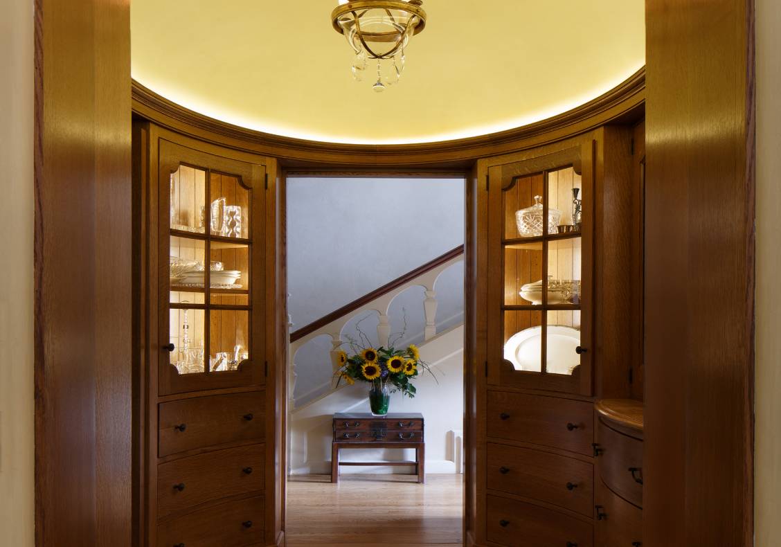 The butler's pantry's floor pattern, domed ceiling and art glass window play off the room's oval geometries.