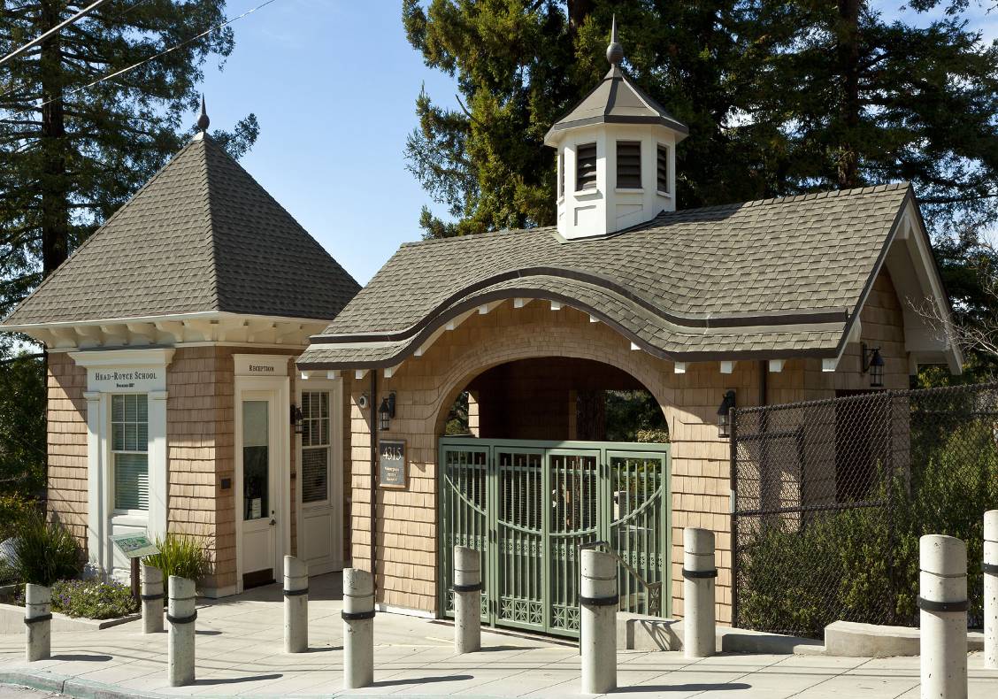 The gatehouse features a painted wood cupola with standing seam copper roof, a cedar shingle exterior, and an elliptical opening framed by an eyebrow roof.