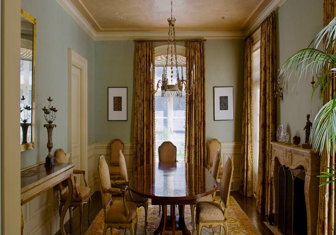 The dining room's pale green walls and creamy white wainscot are a counterpoint to the golden hue of the jacquard curtains and Persian carpet.