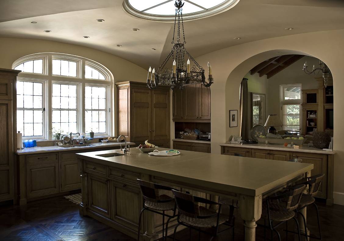 The large kitchen island provides a central gathering point and informal dining space for the family. The ceiling has a large elliptical skylight that fills the room with warm, natural light.