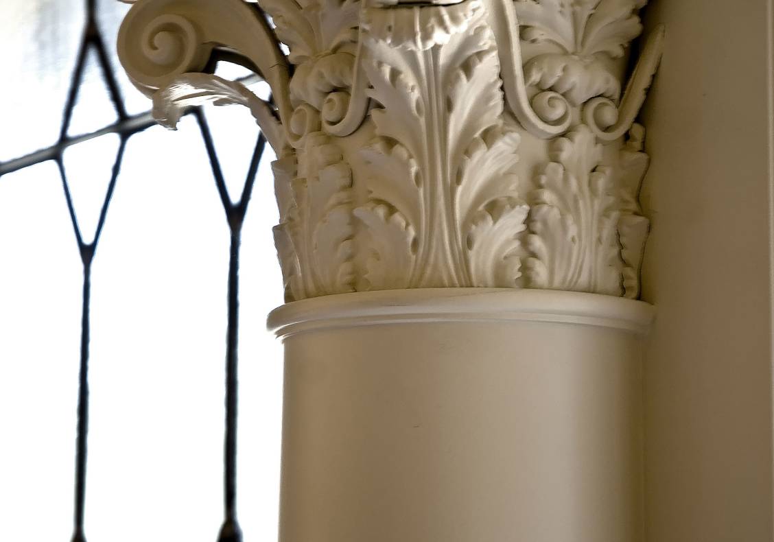 A Corinthian capital graces the wall between the master bathroom's leaded glass windows.