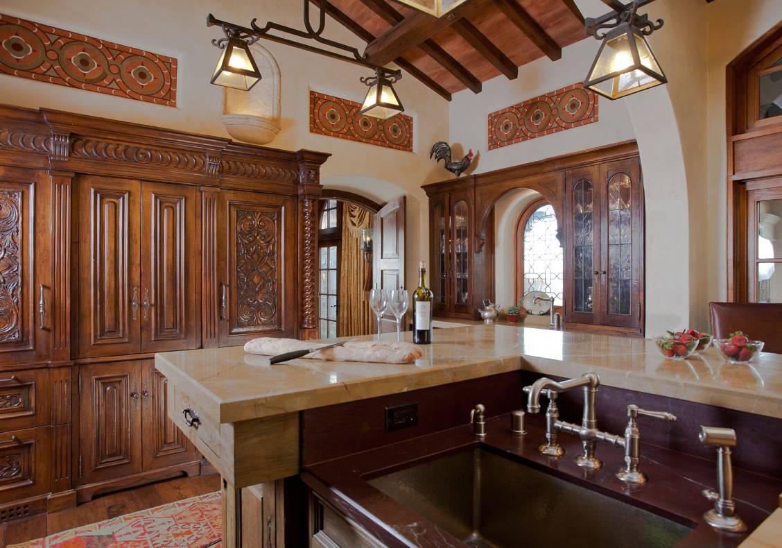 The rusticity of the kitchen island complements the refinement of the surrounding cabinets.