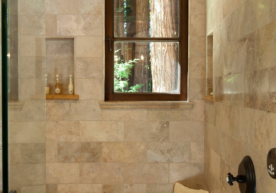 Walnut travertine walls with a brick laid tile ceiling make a grotto-like shower that looks into the understory of a grove of California redwoods.