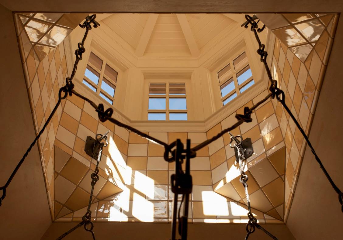 During the day, the kitchen receives natural light from a two-story oculus which supports a wrought iron pot rack and chandelier.