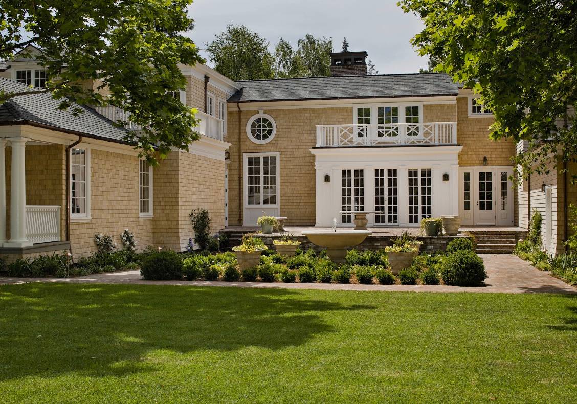 Painted white exterior trim was added to existing windows while new oval, round and tall French windows and doors provide architectural accents to the elevations.