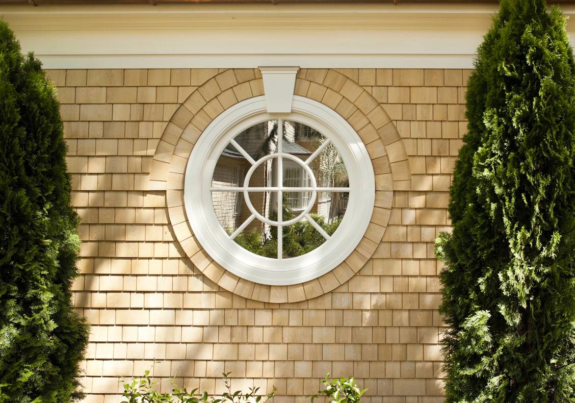 The shingles articulate the mirrored oculus at the new pool house.
