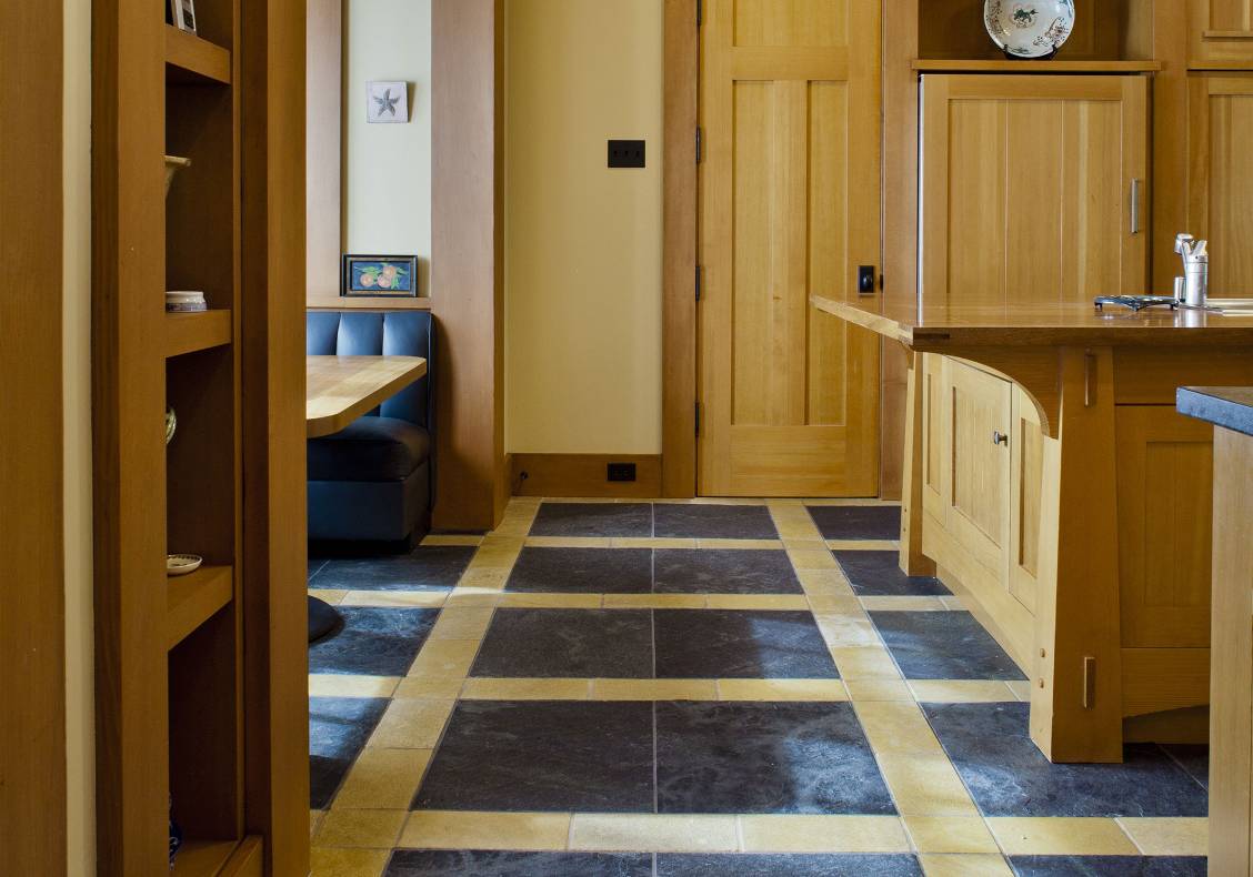 Emerald green slate tiles framed by honed tumbled empire gold stone tiles. Stained wood island with an exotic wood countertop. Build-in refrigerator with custom wood panels.