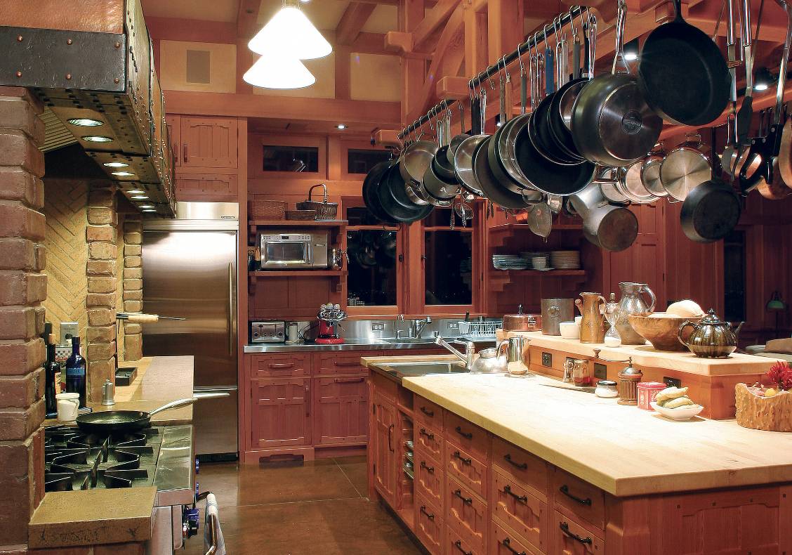 Leaded glass laylights by Theodore Ellison bring warm light into the large kitchen. The island is filled with vertical grain douglas fir cabinetry with mortise and tenon joinery. A cloud-lift truss pot rack designed by our office holds ample pots and pans. A 10' long hammered copper hood serves the professional range and wood burning cooking hearth.