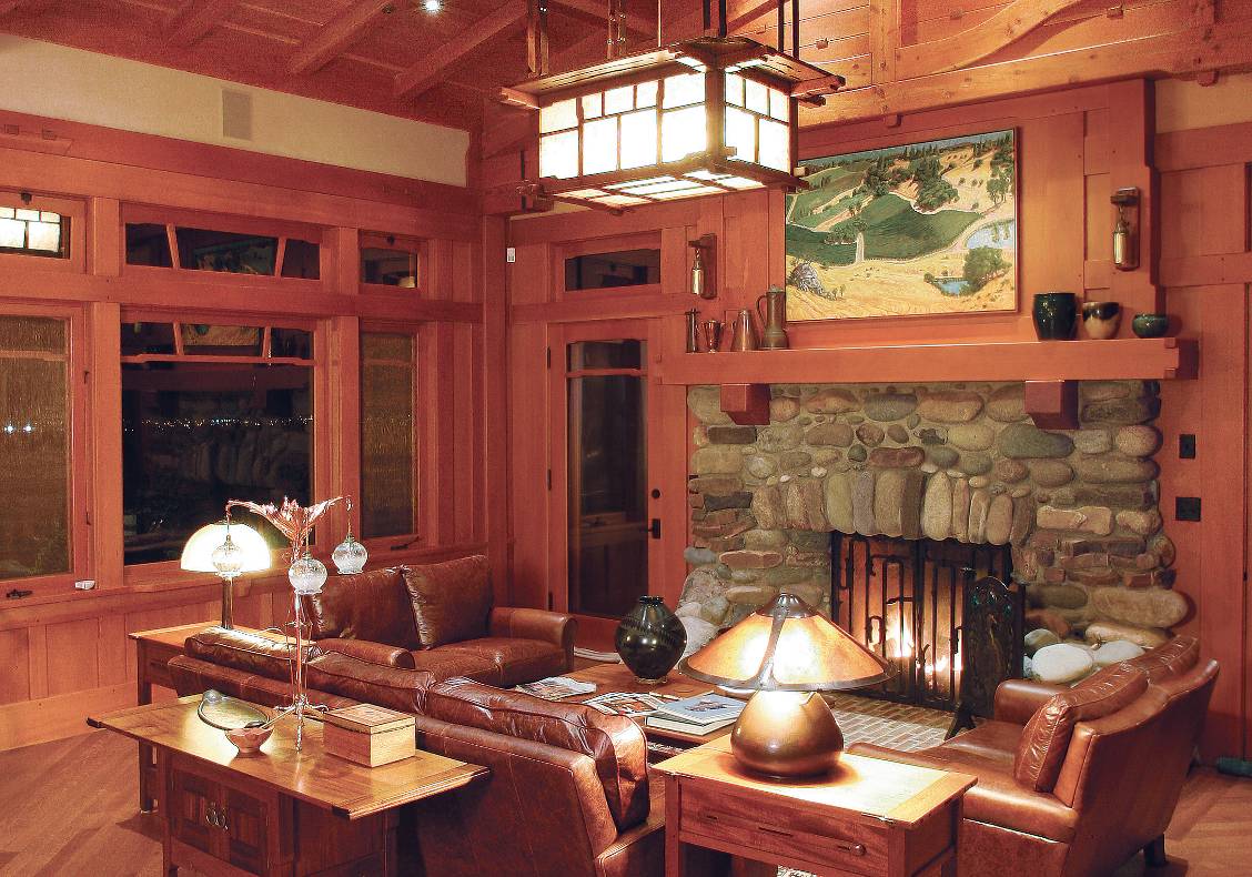 View of great room with custom designed heavy timber trusses and large 'cloud-lift' windows, rock fireplace and hand crafted iron fireplace doors.