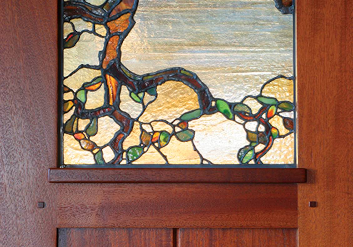 Oversized entry door with oak tree stained glass panels completes the arts and crafts entrance to the home.